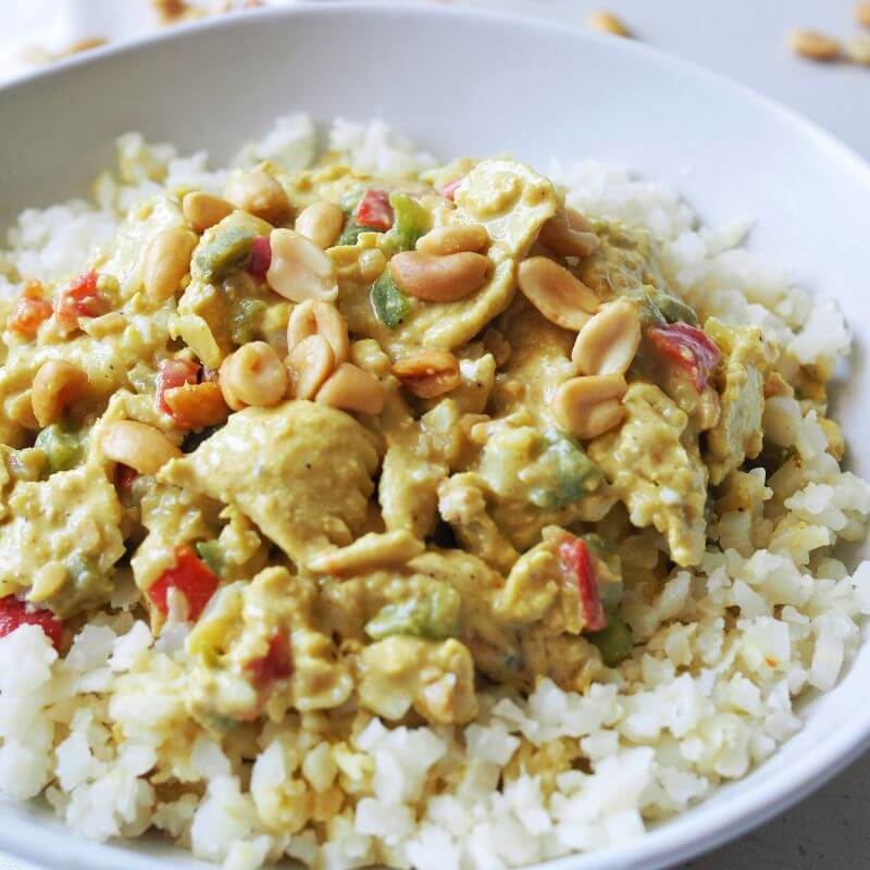 A close-up view of the Satay Chicken with cauliflower rice and capsicum, showcasing the creamy peanut sauce and vibrant garnishes of chopped spring onion. The texture of the cauliflower rice and the richness of the satay sauce are highlighted in this detailed shot.